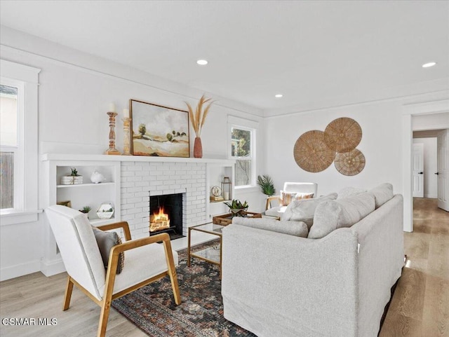 living room with light wood-type flooring and a brick fireplace