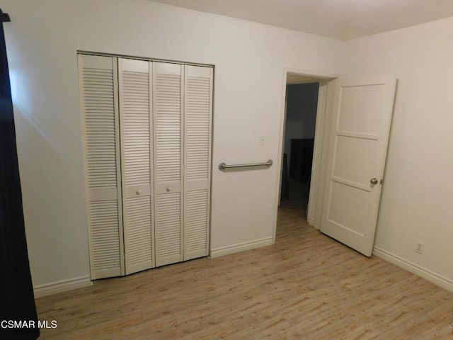 unfurnished bedroom with a closet and light wood-type flooring