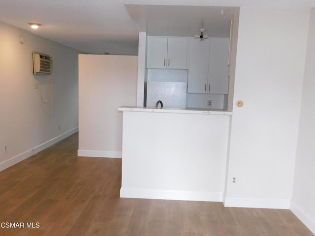 kitchen featuring white cabinets, wood-type flooring, white refrigerator, and a wall mounted air conditioner