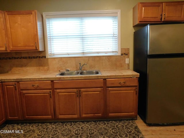 kitchen featuring tasteful backsplash, sink, and stainless steel refrigerator