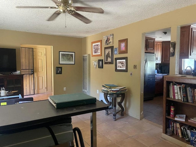 kitchen with a textured ceiling, sink, stainless steel refrigerator, ceiling fan, and light tile patterned floors