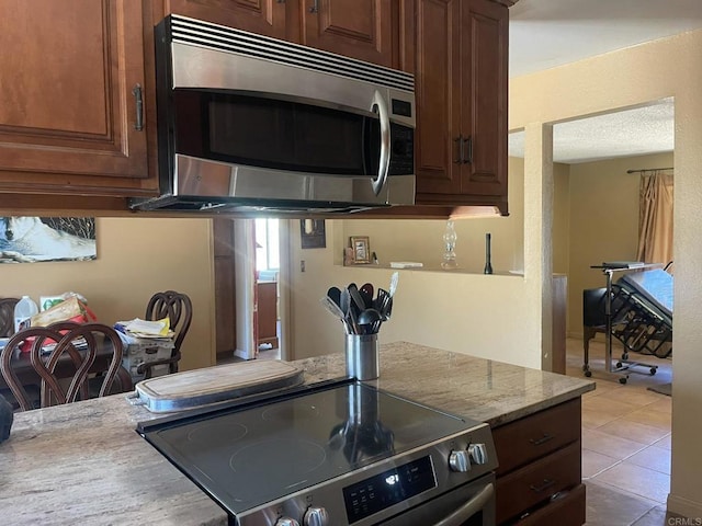 kitchen featuring light stone counters, light tile patterned floors, and appliances with stainless steel finishes