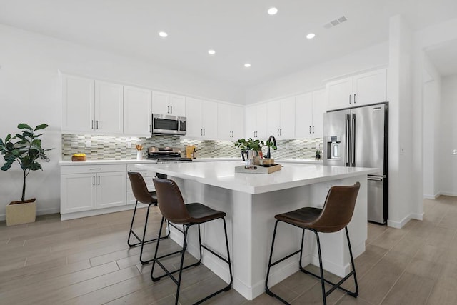 kitchen with backsplash, a kitchen island, appliances with stainless steel finishes, a breakfast bar area, and white cabinets