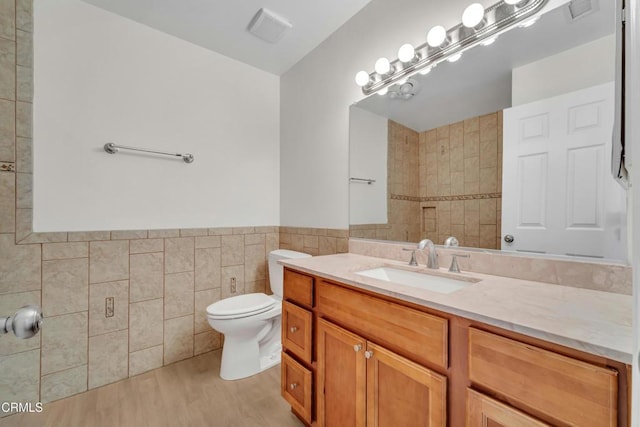 bathroom with tile walls, toilet, vanity, and hardwood / wood-style floors