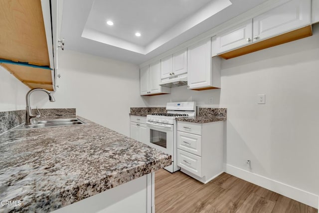 kitchen featuring light hardwood / wood-style flooring, a raised ceiling, sink, white cabinets, and white gas stove