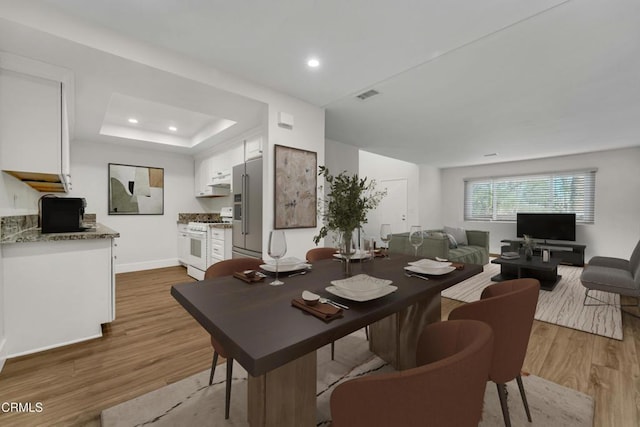 dining room with hardwood / wood-style flooring and a raised ceiling