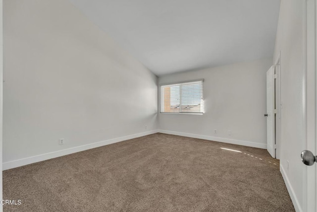 empty room featuring vaulted ceiling and carpet flooring