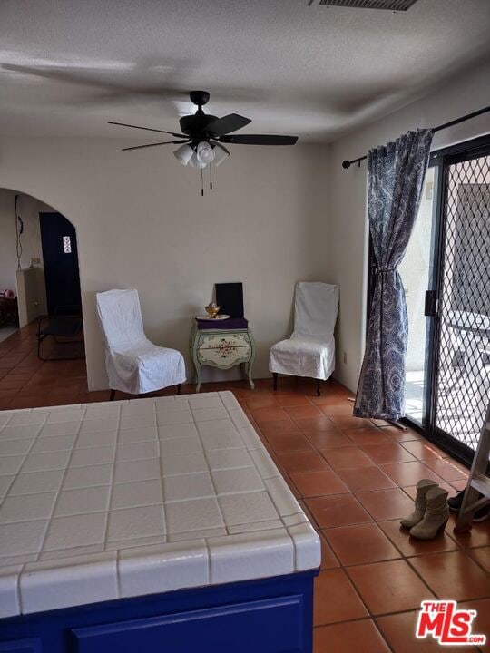 unfurnished bedroom featuring a textured ceiling, ceiling fan, tile patterned flooring, and multiple windows