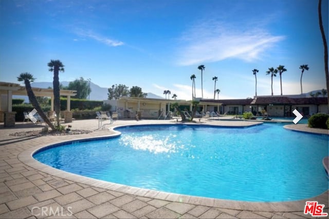 view of swimming pool featuring a mountain view and a patio