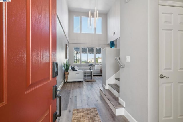 entryway with hardwood / wood-style floors, a towering ceiling, and an inviting chandelier