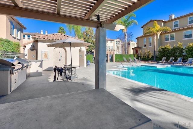 view of swimming pool with a patio area, an outdoor kitchen, grilling area, and a pergola