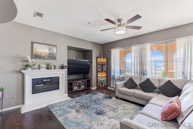 living room featuring ceiling fan and dark wood-type flooring