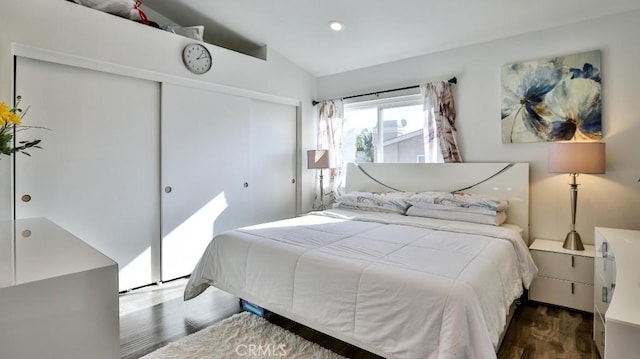 bedroom featuring a closet, dark wood-type flooring, and lofted ceiling