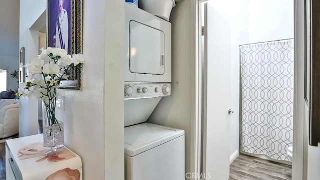 clothes washing area featuring light hardwood / wood-style floors and stacked washer / dryer