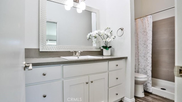 bathroom featuring hardwood / wood-style floors, toilet, walk in shower, and vanity