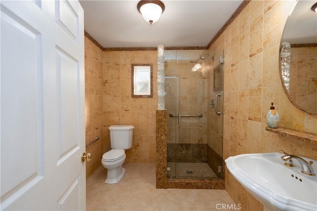 bathroom featuring toilet, tile patterned flooring, tile walls, walk in shower, and sink