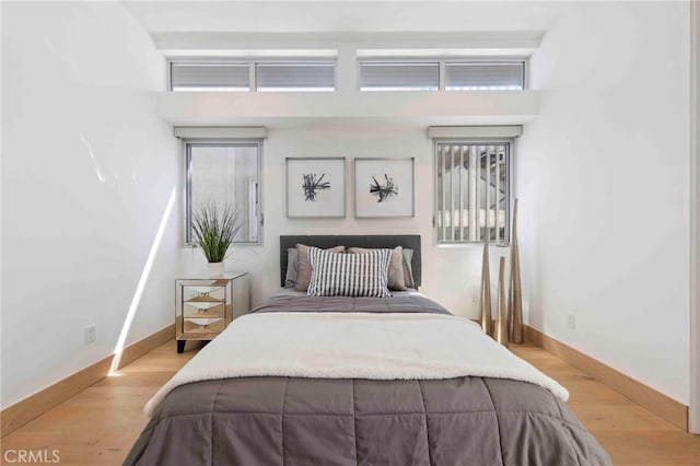 bedroom featuring a towering ceiling and light wood-type flooring