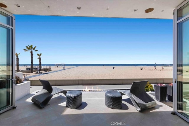 view of patio featuring a water view and a beach view