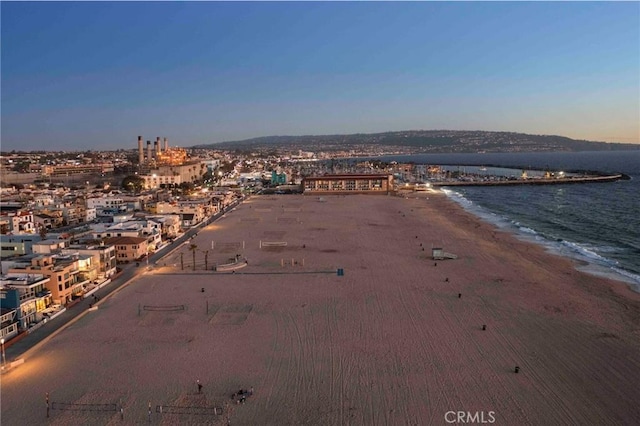 aerial view at dusk featuring a beach view and a water view