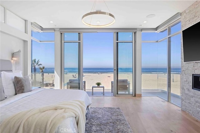 bedroom featuring multiple windows, expansive windows, and a stone fireplace