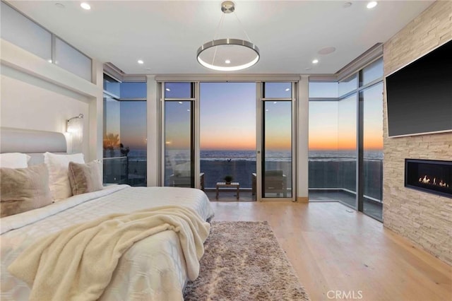 bedroom featuring light wood-type flooring, a wall of windows, and a fireplace