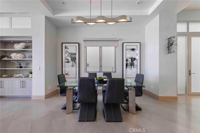 dining room with built in shelves, light tile patterned floors, and a tray ceiling