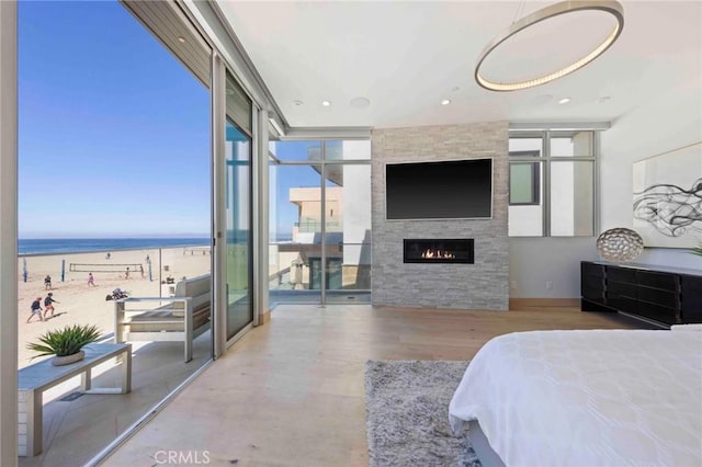 bedroom with a fireplace, a wall of windows, and a water view