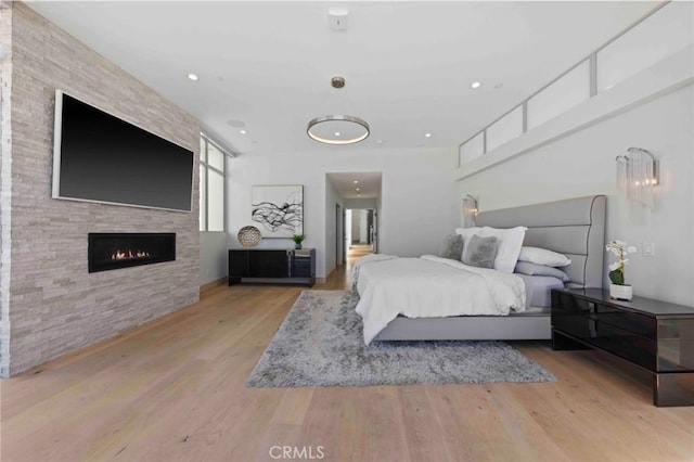 bedroom featuring light hardwood / wood-style flooring and a stone fireplace