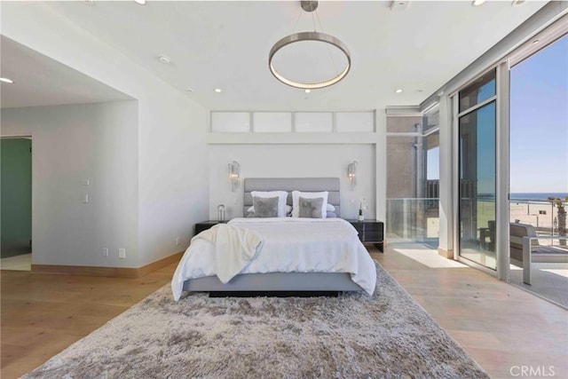 bedroom with a water view, floor to ceiling windows, and hardwood / wood-style flooring