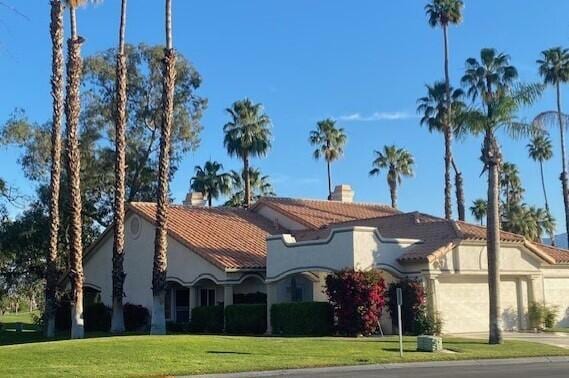 mediterranean / spanish-style home featuring a garage and a front lawn