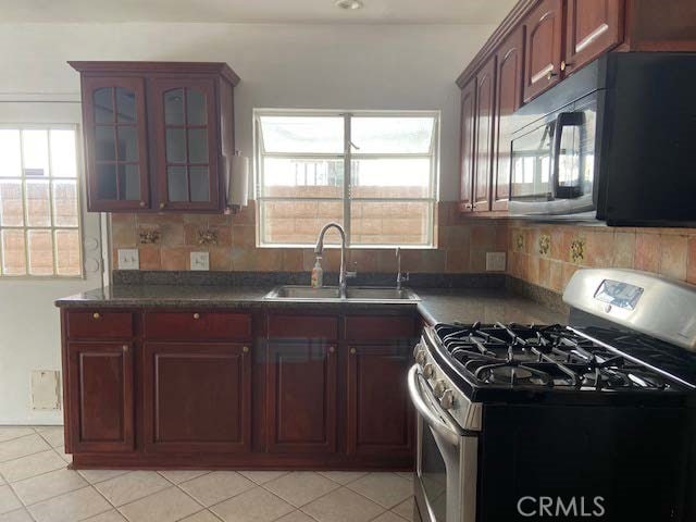 kitchen featuring stainless steel gas range, light tile patterned floors, tasteful backsplash, and sink