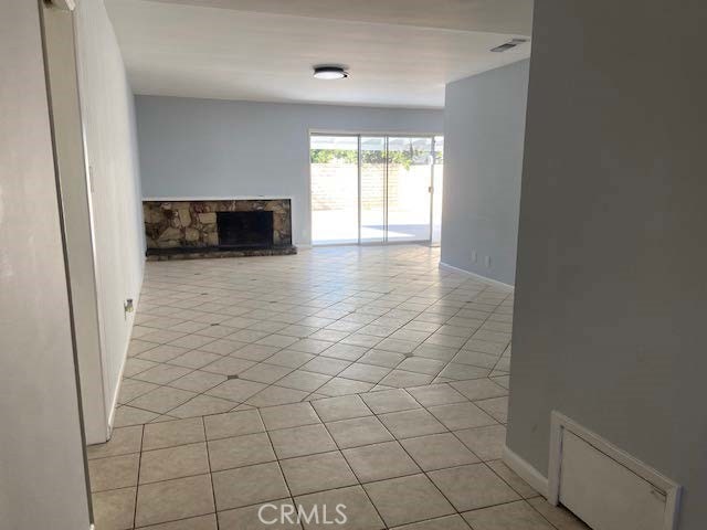 unfurnished living room featuring light tile patterned floors and a stone fireplace