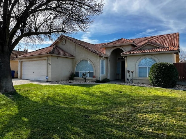 mediterranean / spanish home featuring a front yard and a garage