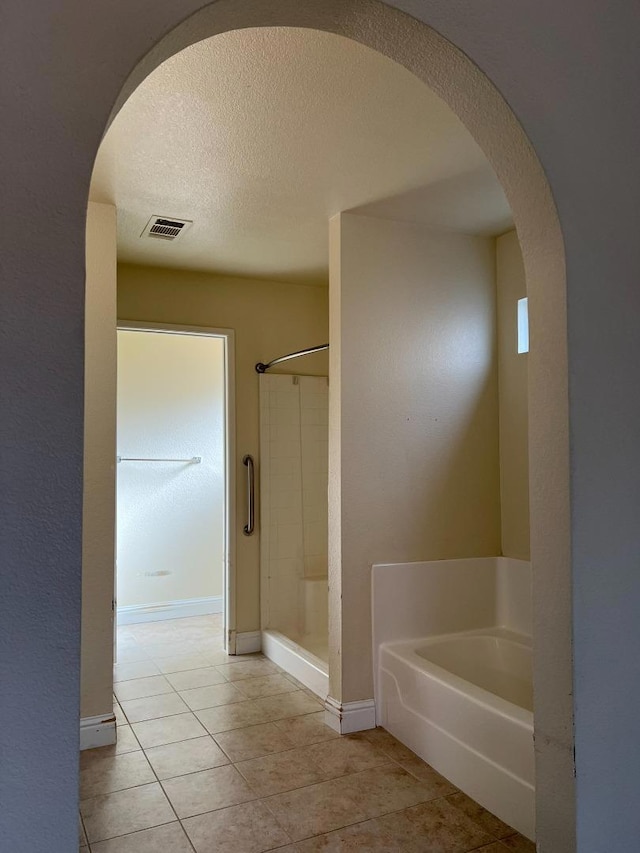 bathroom featuring tile patterned flooring, shower with separate bathtub, and a textured ceiling