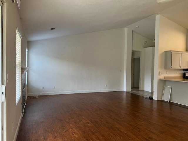 unfurnished living room featuring dark wood-type flooring and high vaulted ceiling