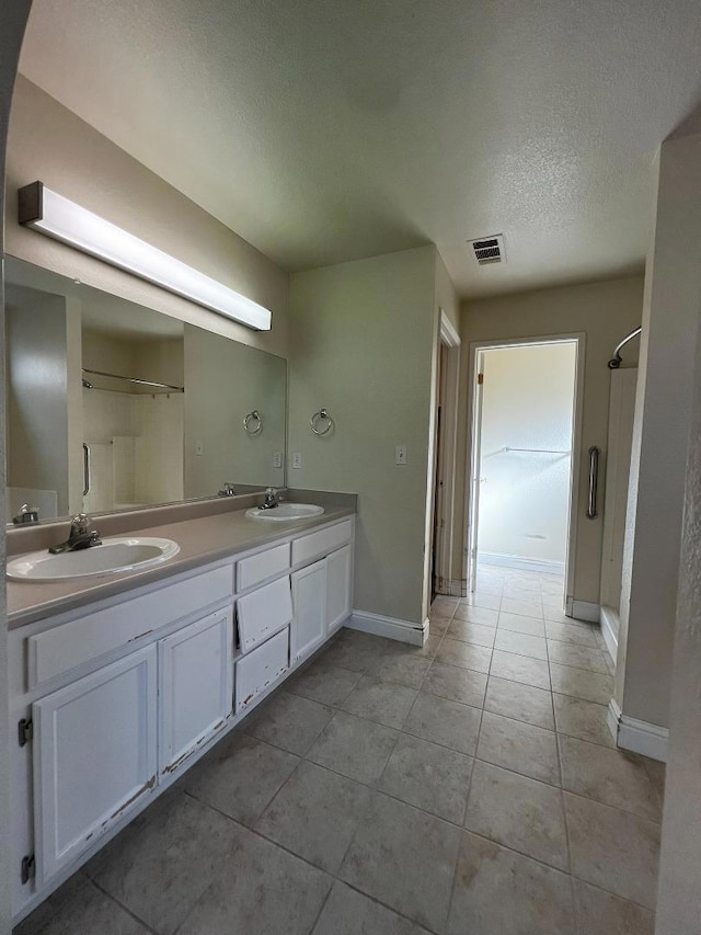 bathroom with tile patterned flooring, vanity, a shower, and a textured ceiling