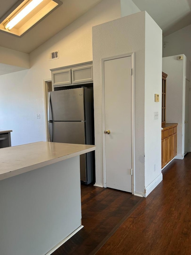 kitchen with dark wood-type flooring, stainless steel fridge, black dishwasher, and vaulted ceiling