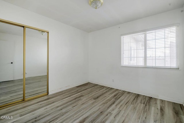 unfurnished bedroom with a closet and light hardwood / wood-style flooring