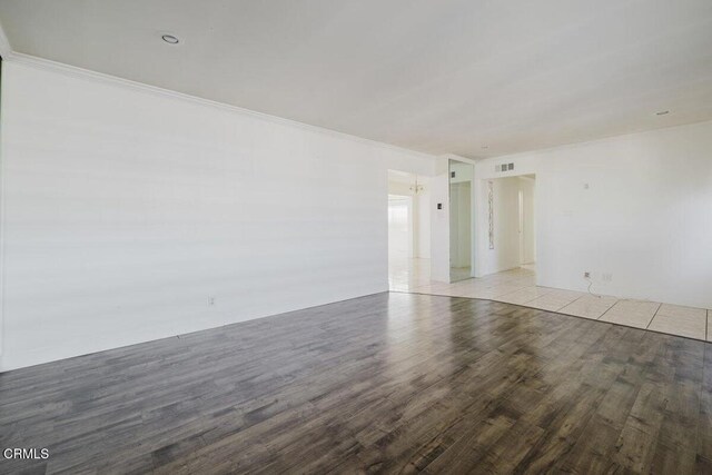 spare room featuring light wood-type flooring and crown molding