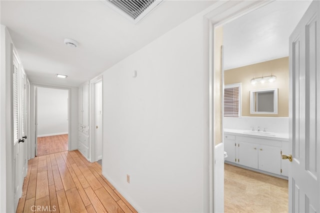 hall with light wood-type flooring and sink