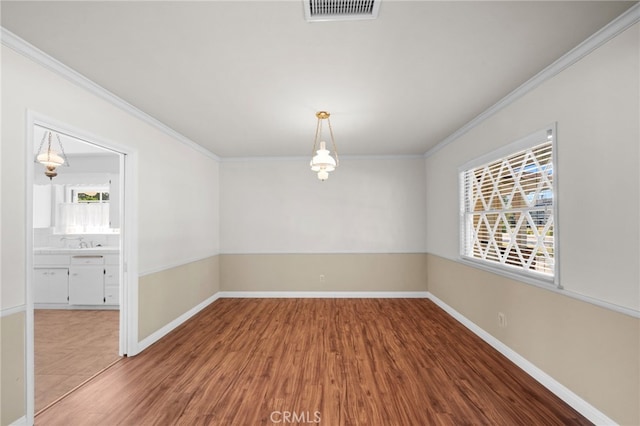 empty room with hardwood / wood-style flooring and crown molding