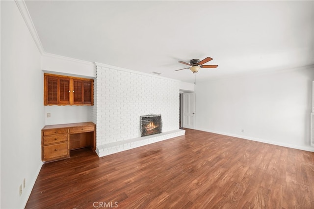 unfurnished living room featuring ceiling fan, dark hardwood / wood-style flooring, crown molding, and a fireplace