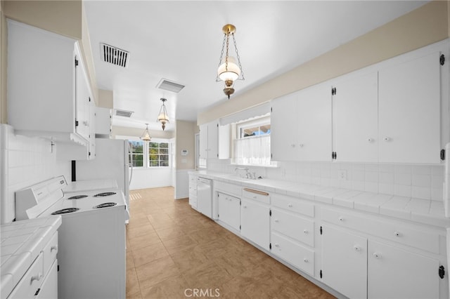 kitchen with hanging light fixtures, white cabinets, and tile counters