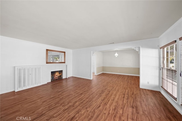 unfurnished living room featuring dark wood-type flooring, a fireplace, and ornamental molding