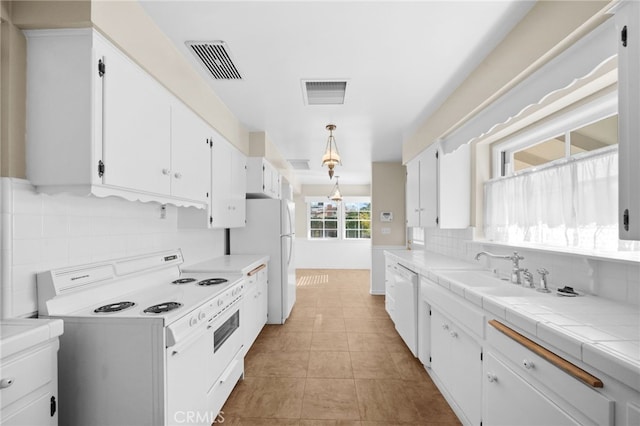 kitchen with tile countertops, decorative backsplash, white cabinetry, and white appliances