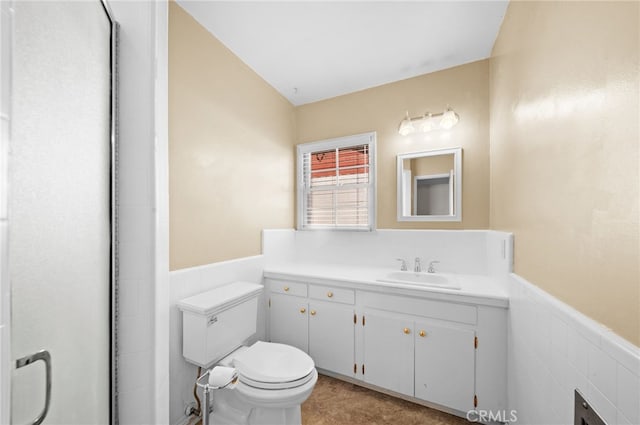 bathroom featuring toilet, vanity, and tile walls