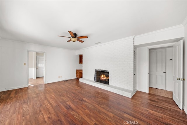 unfurnished living room featuring ceiling fan, dark hardwood / wood-style floors, ornamental molding, and a brick fireplace