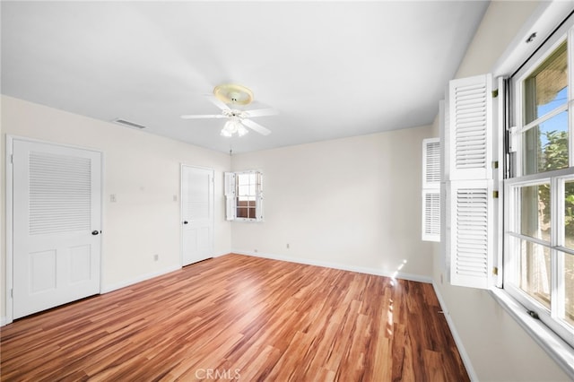 spare room with ceiling fan, a wealth of natural light, and light hardwood / wood-style flooring