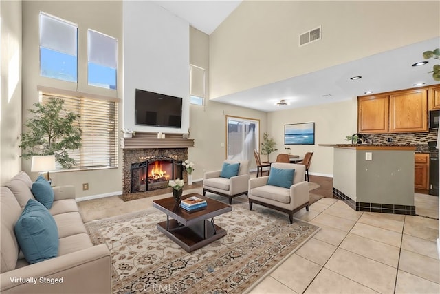 tiled living room featuring a fireplace and a towering ceiling