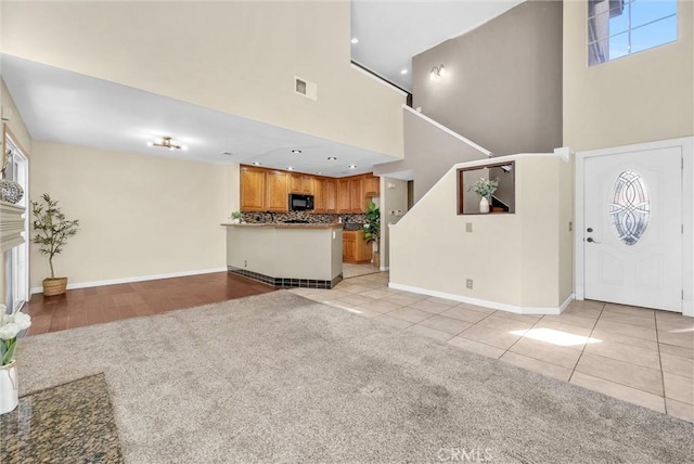 interior space featuring light tile patterned floors, a tiled fireplace, and a high ceiling